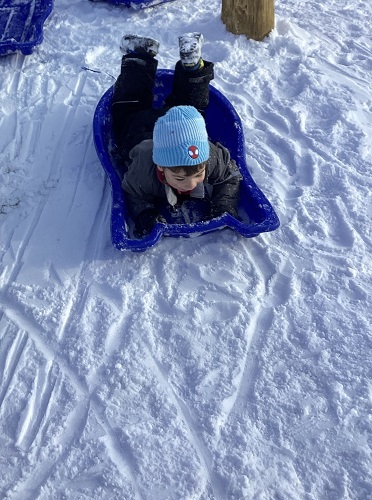 A child sledding on their tummy