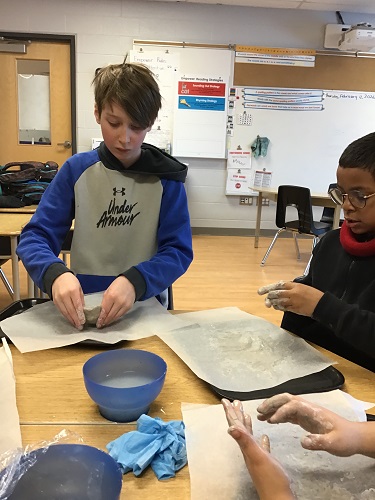 Two children molding clay bowls with their fingers