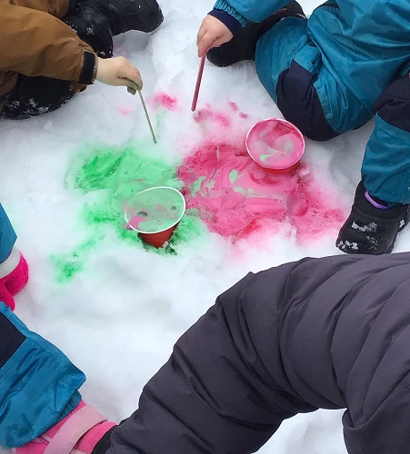 Two toddlers using sticks to explore green and pink foam