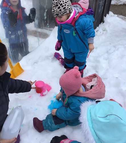 Toddlers watching the reaction when vinegar was added to a cup with baking soda and food pink colouring